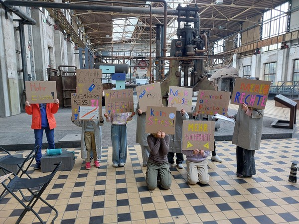 Kinder halten beschriebene Plakate mit verschiedenen Sprüchen hoch