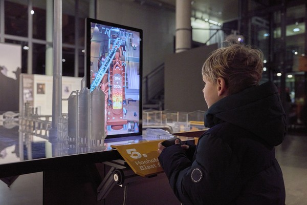 Ein Kind steht an einem Element der Ausstellung "Ans Werk!"