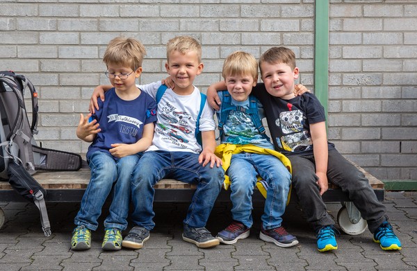 Vier Jungen sitzen auf einer Bank zusammen