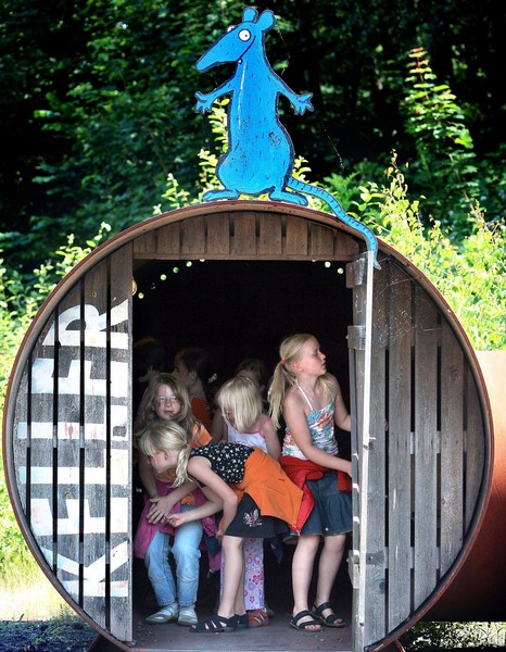 Kinder in einer großen Röhre. Auf dem Dach der Spielstation sitzt das blaue Maskottchen "Ratte".