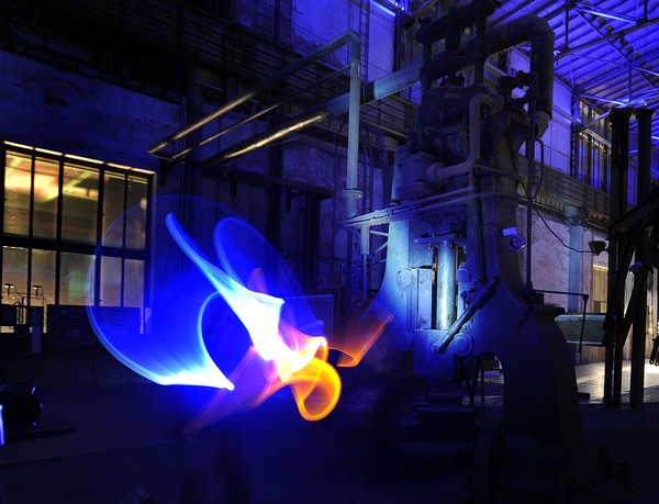 Dunkle Industriekulisse mit bunten Lichtschweifen (entstanden durch Lightpainting). Foto: Simon Leifeling