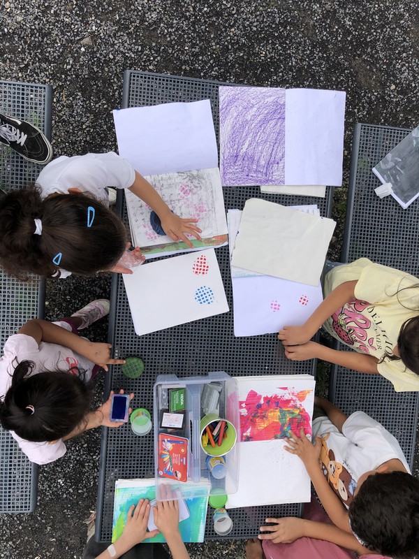 Kinder pausen die Struktur eines Tisches auf dem Hüttengelände mit Farben auf Papier ab